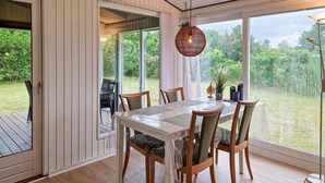 En matplats med ett bord och stolar, stora fönster och en hängande lampa.
