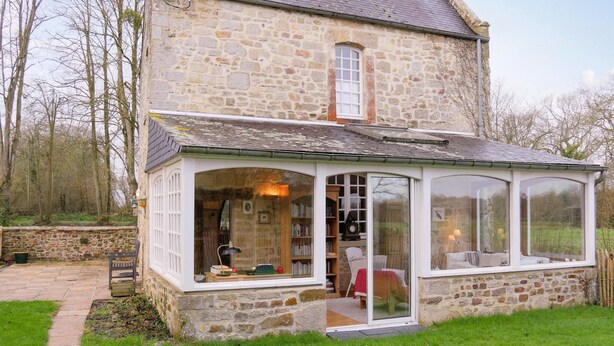 Un bâtiment en pierre doté d’une véranda en verre.