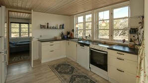 A kitchen with white cabinets, a black stove, and a window with a view of trees. - Lovely home in Anholt with WiFi (Anholt)