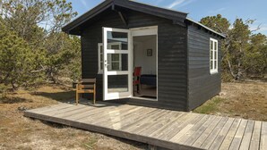 A small cabin with a wooden deck, a single door, and a chair outside. - Lovely home in Anholt with WiFi (Anholt)