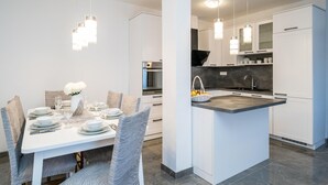 Een moderne keuken met witte kasten, een centraal eiland en hangende lampen.