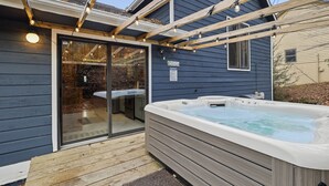 A hot tub outside a house with a wooden deck and a glass door leading to a bathroom. - COZY MOUNTAIN ESCAPE! .5mi frm slopes 50ft to trails. HOT TUB! (Beech Mountain)