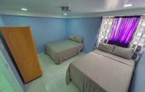 Two single beds with matching bedspreads and a wooden wardrobe are featured in this cozy bedroom.