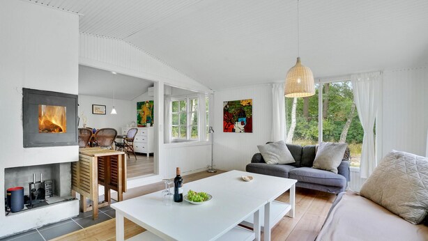A modern living room with a fireplace, a dining area, and a sofa with a view of the outdoors. - Beautiful home in Melby with kitchen (Melby)