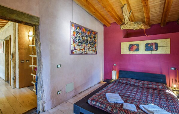 A bedroom with a bed, a wooden ceiling, and a colorful abstract painting on the wall. - 4 bedroom lovely home in Cedegolo (Cedegolo)