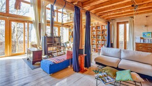 A cozy cabin interior with a wooden interior, a fireplace, a sofa, a bookshelf, and a dining area.