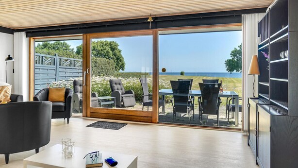 Un salon moderne doté d’une grande porte-fenêtre coulissante donnant sur une terrasse extérieure avec vue sur la mer.