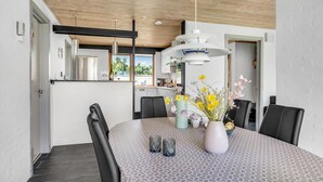 Un espace de salle à manger moderne, doté d’une grande table, de chaises et d’un luminaire suspendu.
