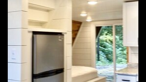 Eine kompakte Küche mit weißen Schränken, einem Edelstahlkühlschrank und einem Fenster mit Blick auf Grünflächen.