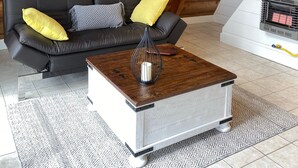 Ein gemütliches Wohnzimmer mit einem schwarzen Ledersofa, einem Holztisch und einem weißen Kamin.