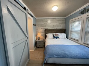 Un dormitorio con una cama, una mesita de noche, una lámpara y un reloj de pared.