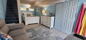 A bedroom with a bed, dresser, and a staircase.