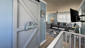 Un salon doté d’une porte coulissante, d’un ventilateur de plafond et d’un téléviseur fixé au mur.