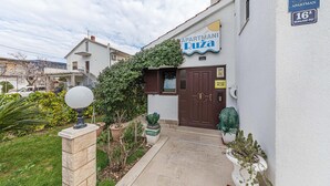 Un edificio con un cartel que dice "APARTMANI DUZA" y un letrero azul que indica "SOBE APARTMAN".