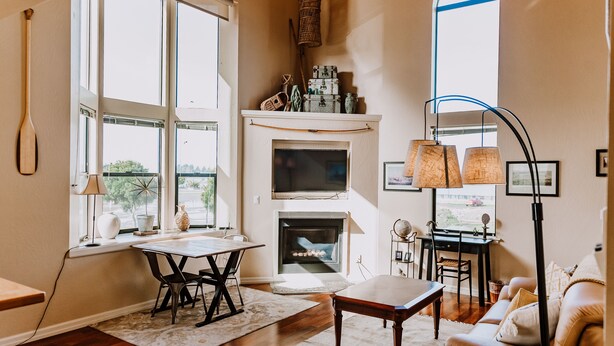 A living room with a fireplace, a dining area, and a large window with multiple panes. - Boardwalk Loft w/bay view loacated in old town (Eureka)
