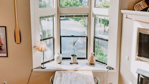 A room with a large window, a table, a lamp, and a fireplace. - Boardwalk Loft w/bay view loacated in old town (Eureka)