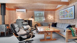 Una habitación acogedora con decoración de madera, un sofá, una silla, una mesa y una chimenea.