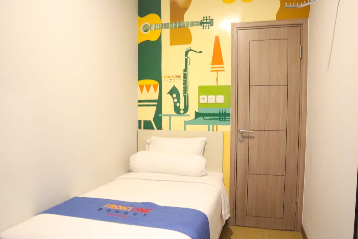 A hotel room with a bed, a wooden door, and a wall with musical instrument illustrations.