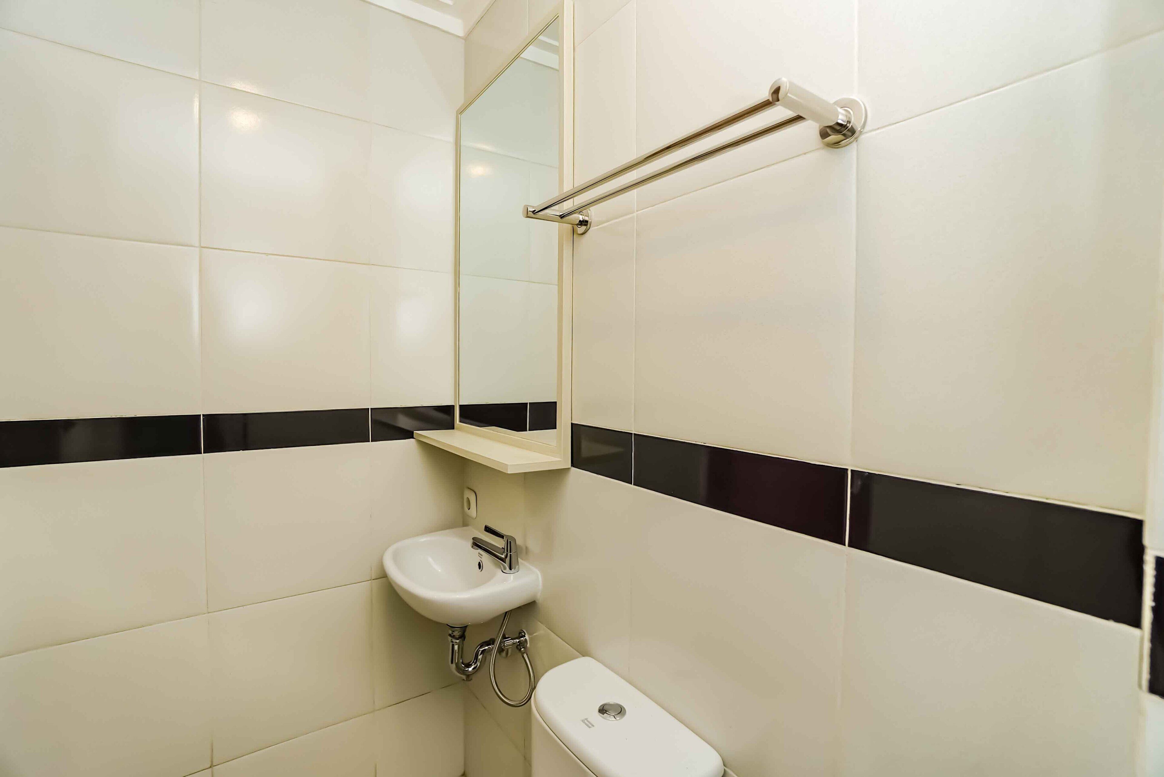 A bathroom with white tiles, a sink, a mirror, and a towel rack.