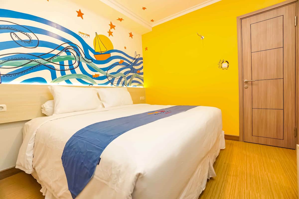 A hotel room with a bed, a wall mural, a wooden door, and a yellow wall.