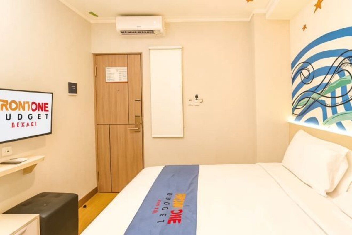 Una habitación de hotel con cama, televisor, armario y una pared con diseño decorativo.