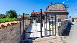 A stone house with a tiled roof, a gated entrance, and a paved pathway leading to the house. - 4 bedroom lovely home in Hrboki (Hrboki)