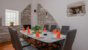A dining area with a stone wall, a window with blinds, and a small shelf with decorative items. - 4 bedroom lovely home in Hrboki (Hrboki)