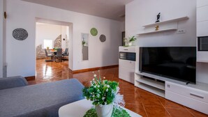 A modern living room with a flat-screen TV, a grey sofa, and a dining area with a table and chairs. - 4 bedroom lovely home in Hrboki (Hrboki)
