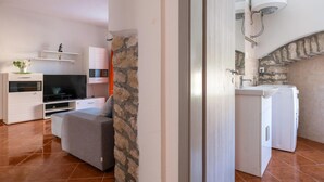 A modern living room with a grey sofa, a flat-screen TV, and a stone accent wall. - 4 bedroom lovely home in Hrboki (Hrboki)