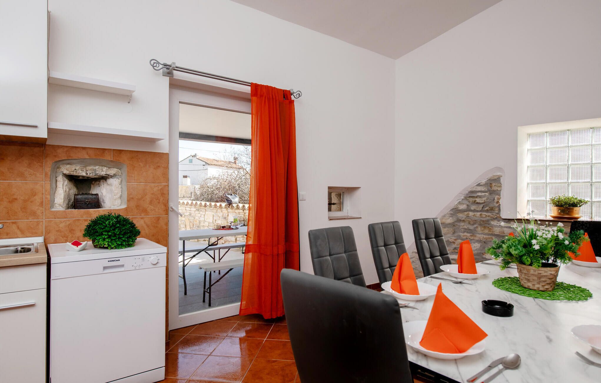 Eine moderne Küche mit Steinwand, einem eingebauten Backofen und einem Essbereich mit Tisch für sechs Personen.
