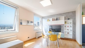 A modern living room with a dining area, a large window with a city view, and a built-in kitchen with marble backsplash. - Nice apartment in Genova with WiFi (Genova)