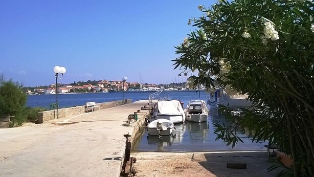 Un port de plaisance avec des bateaux amarrés, un ciel dégagé et une vue lointaine sur une ville.