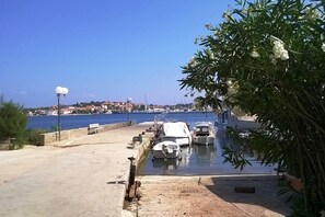 A marina with boats docked, a clear sky, and a distant view of a town.