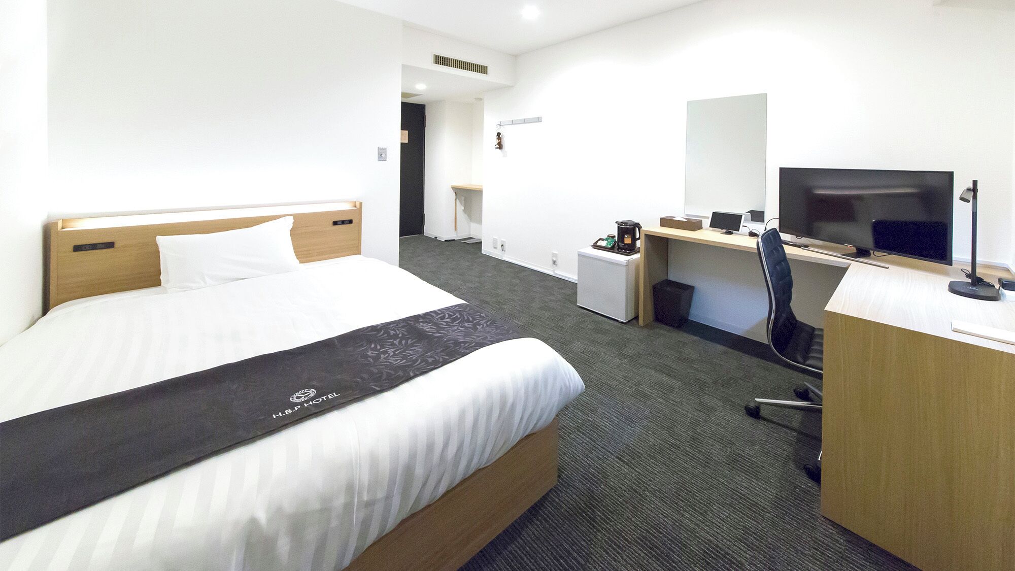 Una habitación de hotel con cama, escritorio, silla, televisor y cafetera.