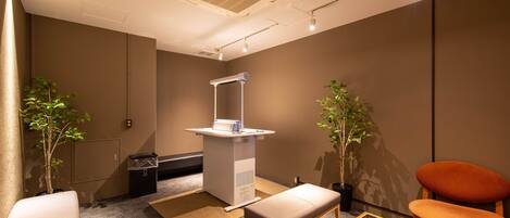 A modern waiting area with a reception desk, seating, and potted plants.