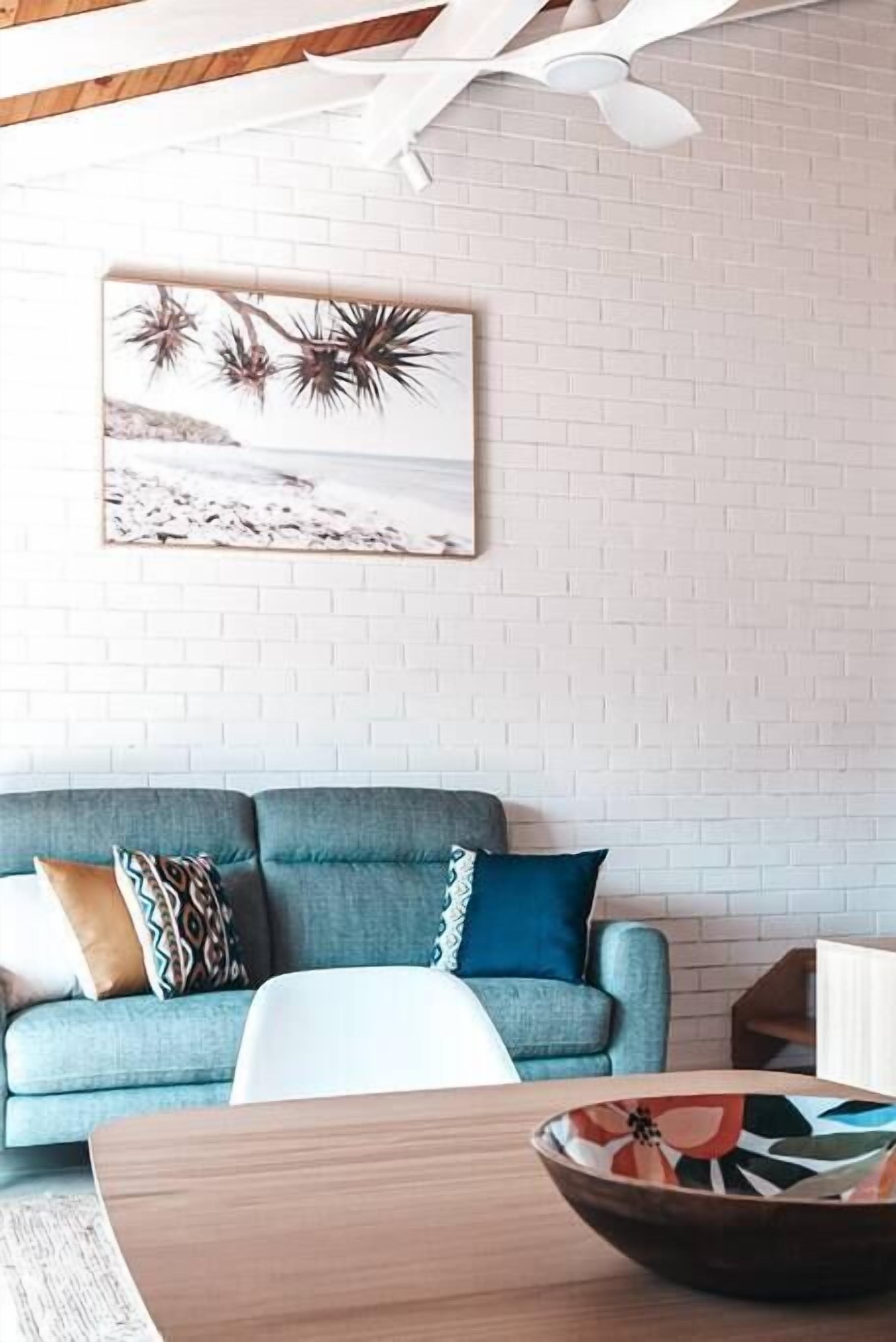 A living room with a blue sofa, a white coffee table, and a framed picture on the wall.