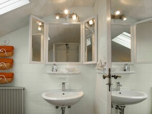 A bathroom with two sinks, a shower, and a mirror with lights.