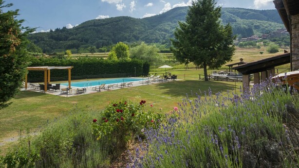Un espace piscine agrémenté d’une pergola, de coins salon extérieurs et offrant une vue sur les montagnes.