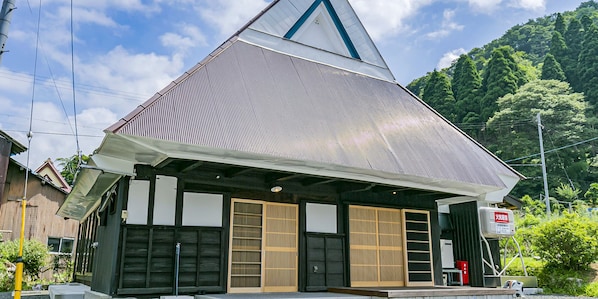 A traditional Japanese building with a sloped roof, wooden doors, and a small porch area.