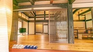 Una habitación amplia con suelo de madera, un gran puertas correderas y una fila de zapatos al frente.