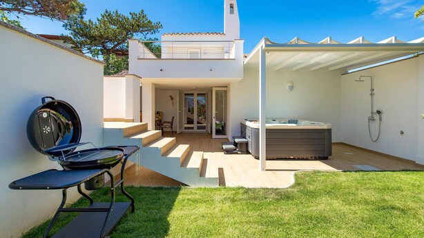Un patio exterior moderno con una parrilla, un jacuzzi y una zona de ducha cubierta.