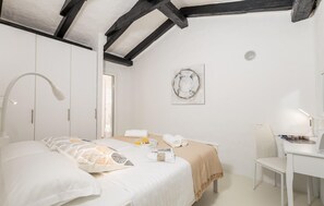A bedroom with a bed, a desk, and a chair. There is a window with blinds, a wall-mounted artwork, and a ceiling fan. - Gorgeous home in Lopar with WiFi (Lopar)