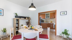 Una cocina moderna con armarios de madera, una mesa de comedor con cojines rojos y una lámpara colgante.