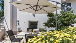 Un patio al aire libre con una mesa, sillas y un paraguas grande.