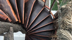 Un escalier en colimaçon au design rustique, fait de métal et de bois, menant à un niveau supérieur.
