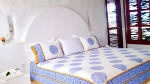 Une chambre à coucher avec un lit, des murs blancs et une fenêtre avec des volets.