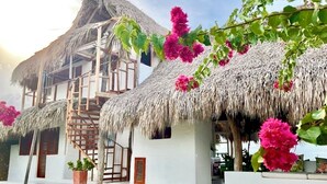 Un bâtiment blanc avec un toit de chaume, un escalier en bois et une plante en pot.