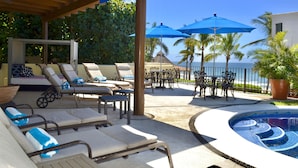 A poolside area with lounge chairs, umbrellas, and a view of the ocean.