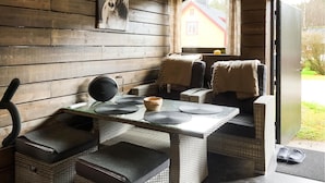 A cozy room with a wooden interior, a glass table, wicker furniture, and a view of a house through a window. - Beautiful home in Reftele with WiFi (Reftele)