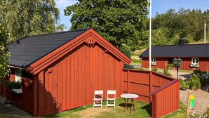A red wooden building with a sloped roof, a small table, and two chairs in front. - Beautiful home in Reftele with WiFi (Reftele)